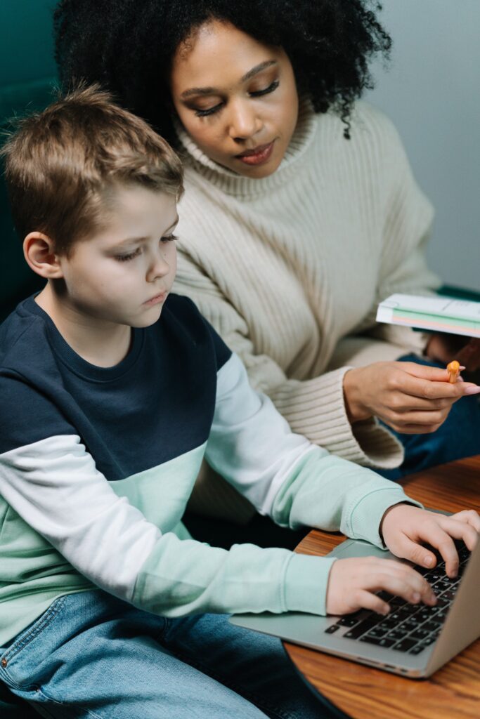pexels photo 6986442 6986442 A dedicated tutor helps a young boy with his homework on a laptop, fostering learning.